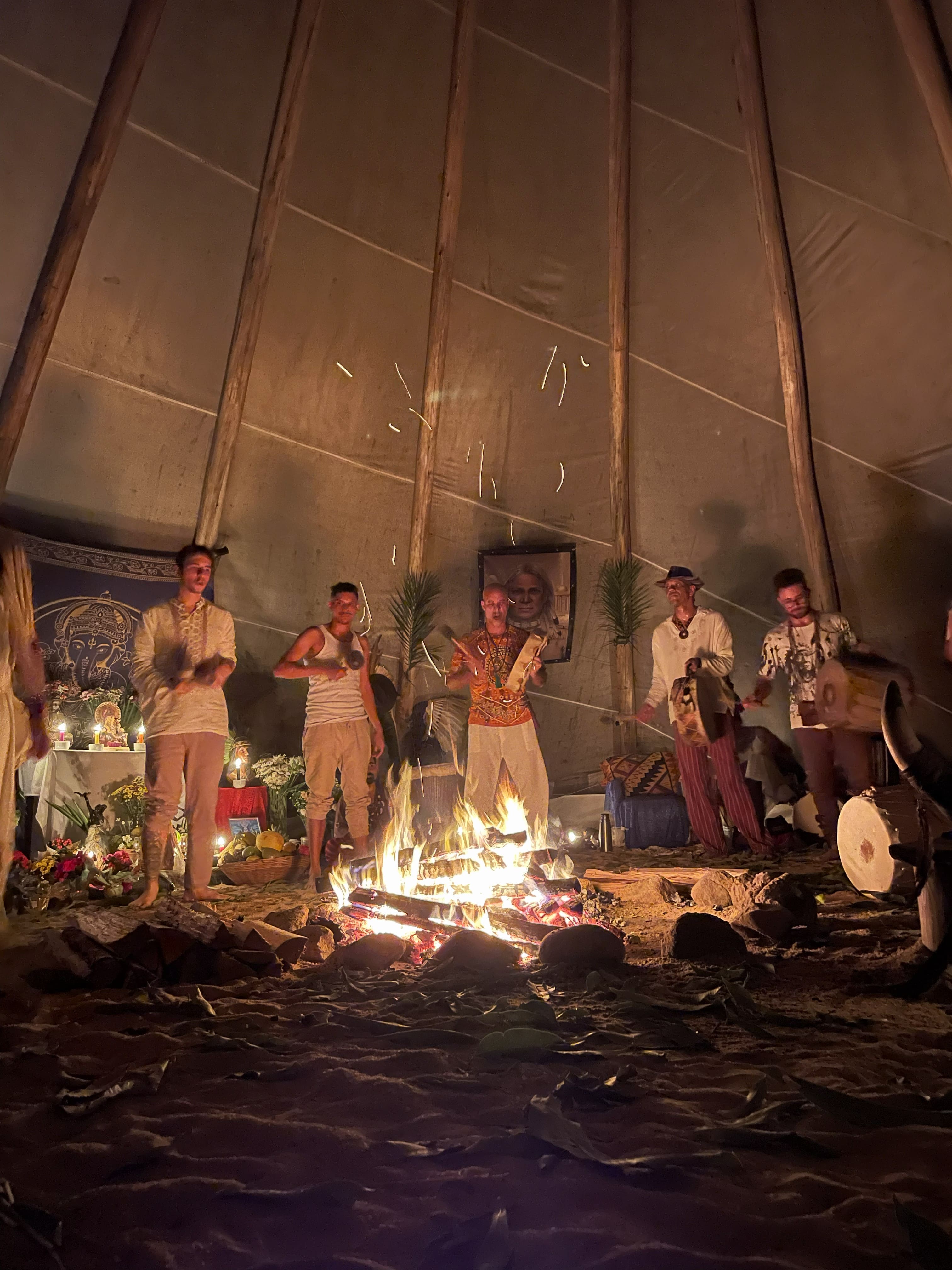 Roda de participantes ao redor do fogo sagrado dentro da tipi, tocando tambores